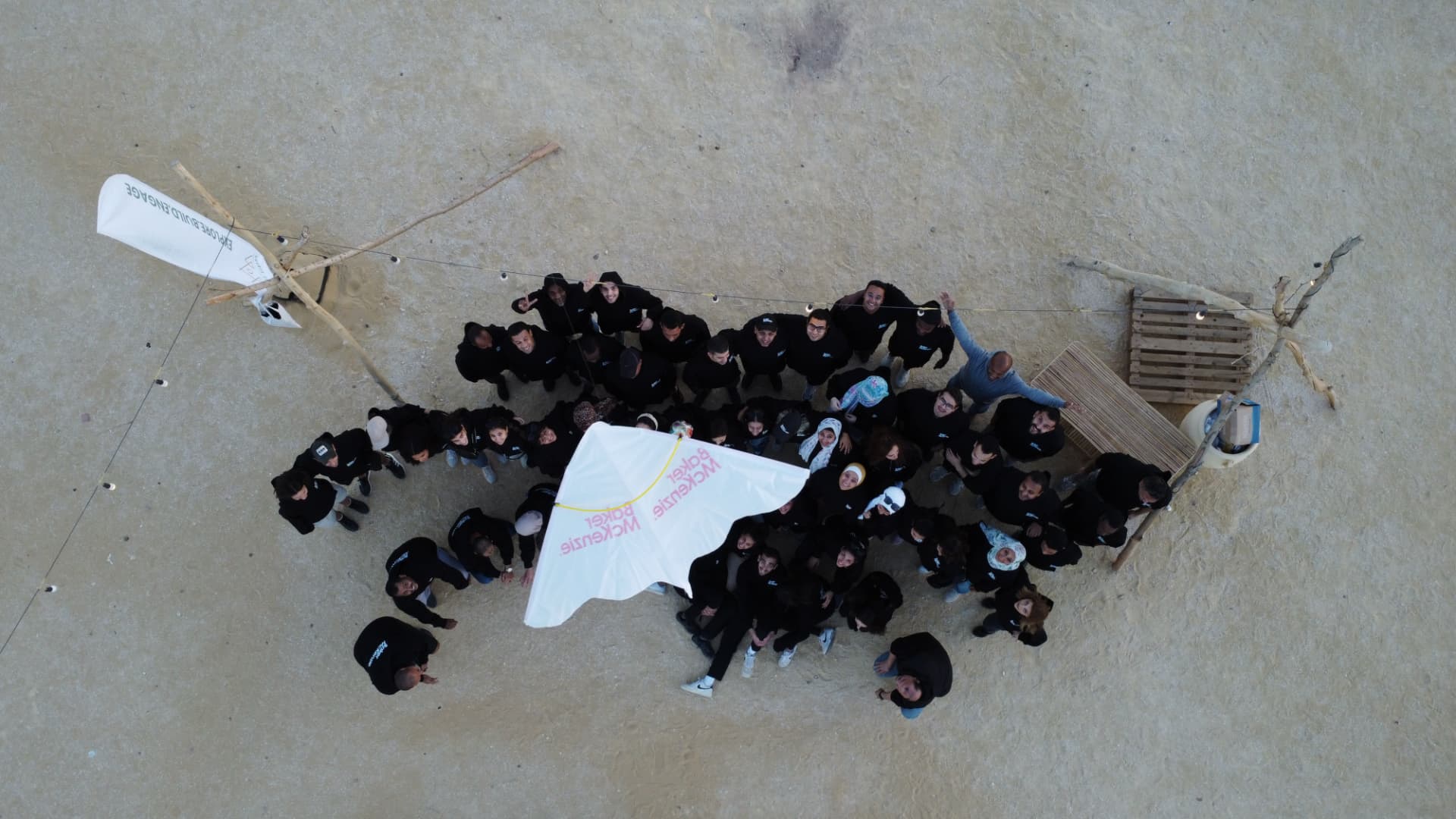 An aerial view of a corporate team gathered in a circle on the sand