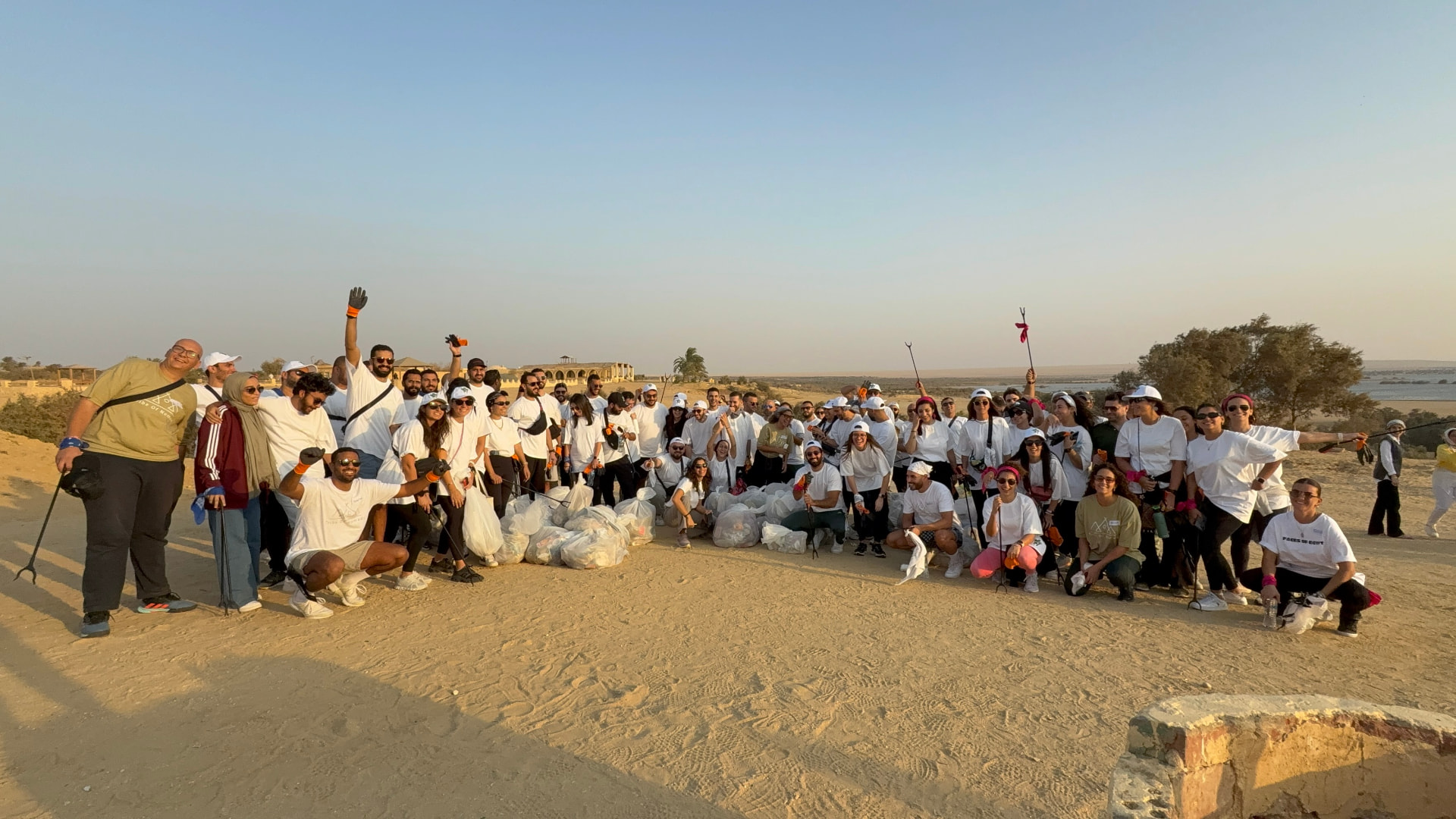 A team celebrating after a beach cleanup CSR activity at sunset
