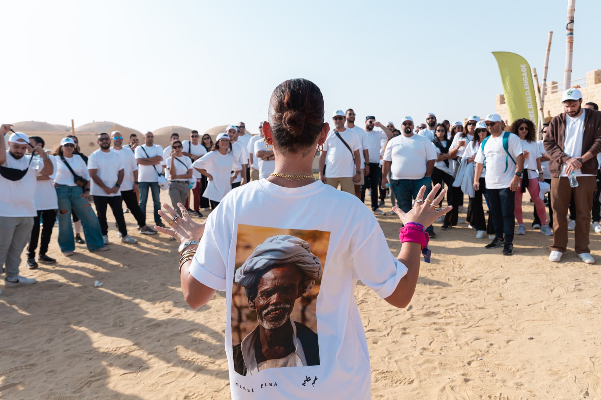 A facilitator briefing a large corporate group at a desert event
